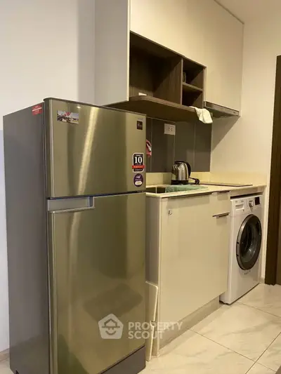 Modern kitchen with stainless steel fridge and washing machine in compact layout.