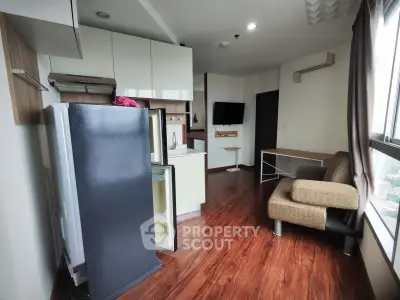 Modern apartment interior with kitchen and living area, featuring sleek appliances and wooden flooring.
