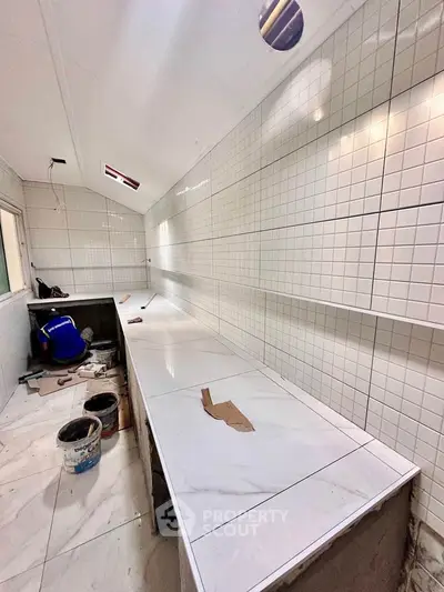 Spacious kitchen under renovation with tiled walls and countertops