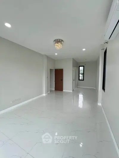 Spacious and bright living room with modern chandelier and large windows.