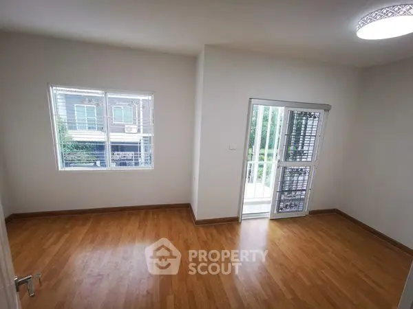 Spacious room with wooden flooring and large windows for natural light