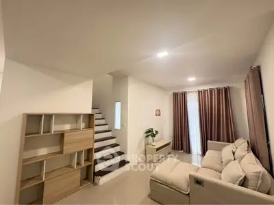 Modern living room with cozy sofa and stylish staircase in a bright interior.