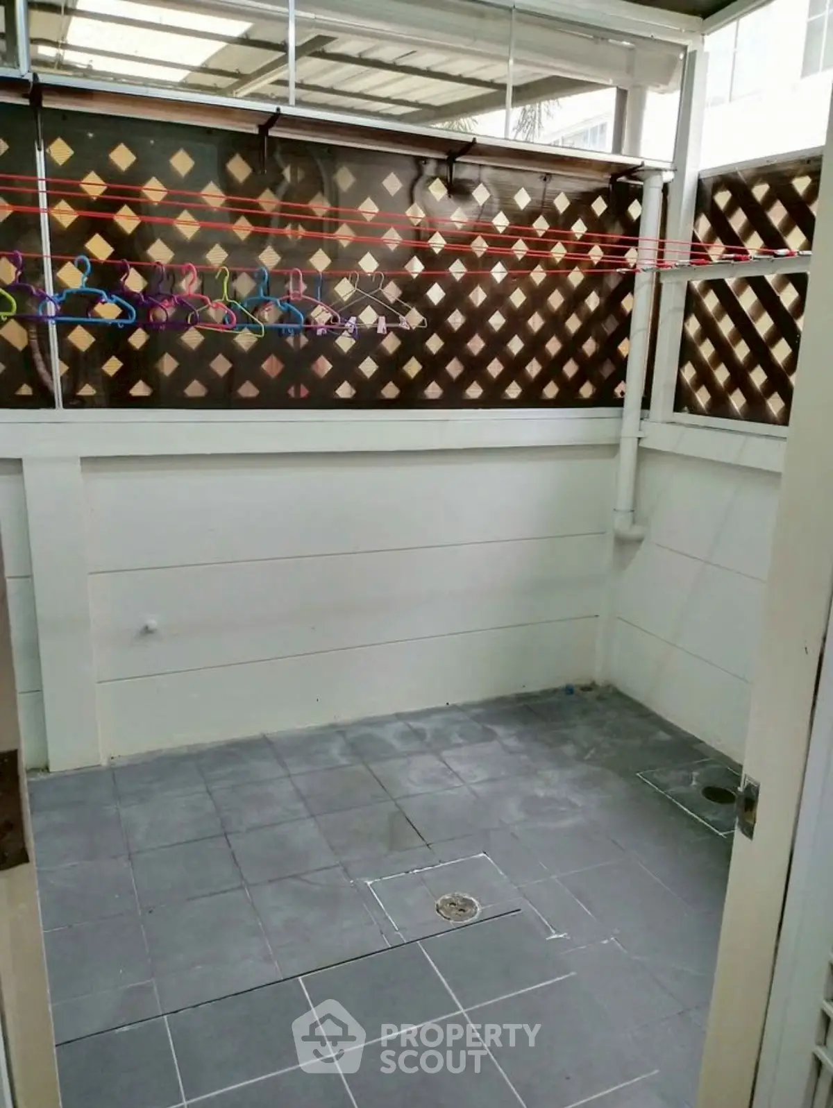 Spacious tiled balcony with privacy lattice and clothesline, perfect for outdoor relaxation.