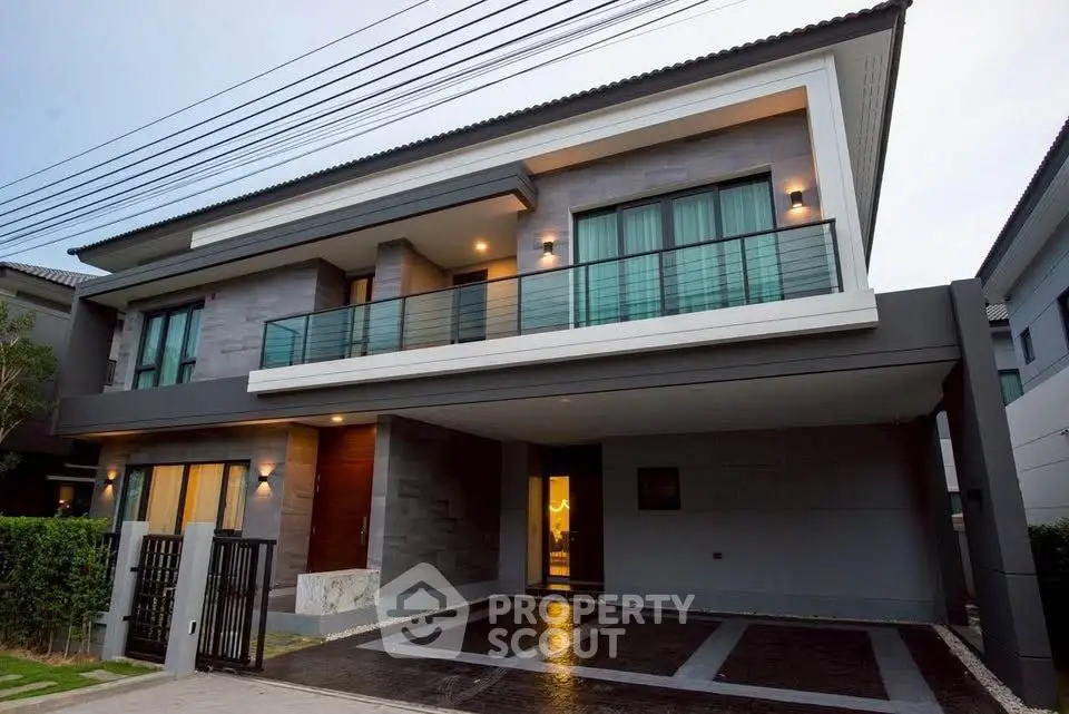 Modern two-story house with sleek balcony and spacious driveway in upscale neighborhood.