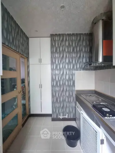 Modern kitchen with sleek design and closed layout, featuring a gas stove and ample storage space.