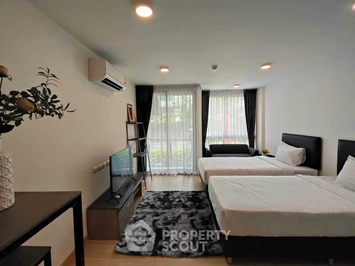 Spacious bedroom with modern decor and large windows for natural light.