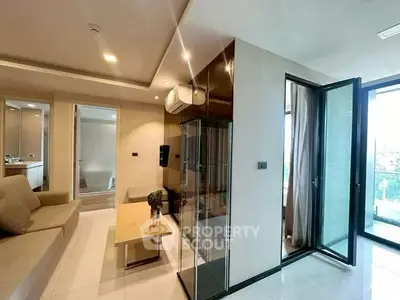 Modern living room with glass doors leading to a balcony, featuring sleek furniture and ambient lighting.