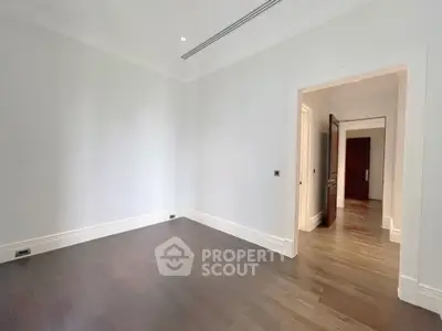 Spacious empty room with elegant hardwood flooring and white walls, perfect for customization.