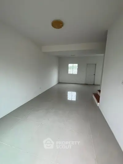 Spacious empty room with glossy tiled floor and white walls, ready for customization.