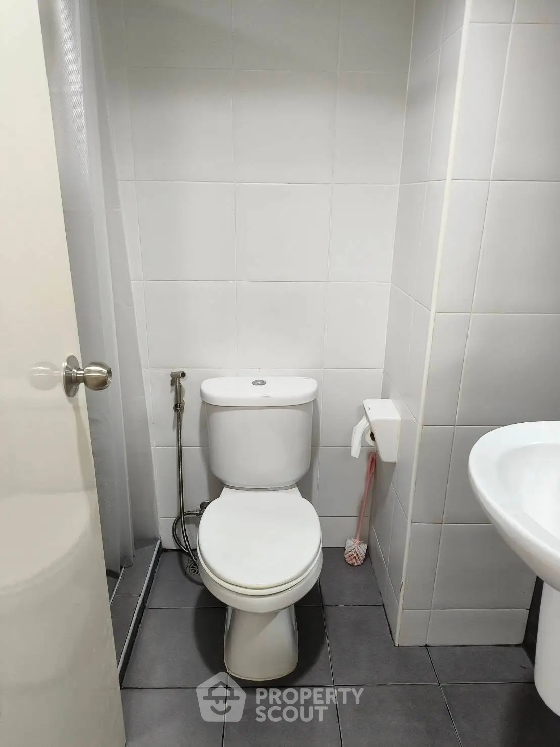 Compact modern bathroom with white tiles and sleek fixtures.