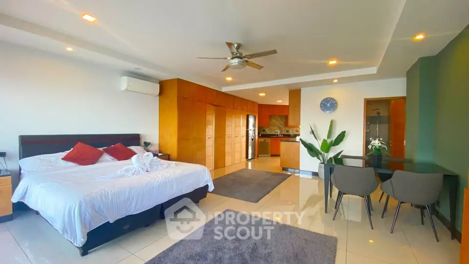 Spacious modern bedroom with open kitchen and dining area, featuring sleek design and ample natural light.