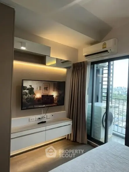 Modern bedroom with balcony view and wall-mounted TV in stylish apartment.