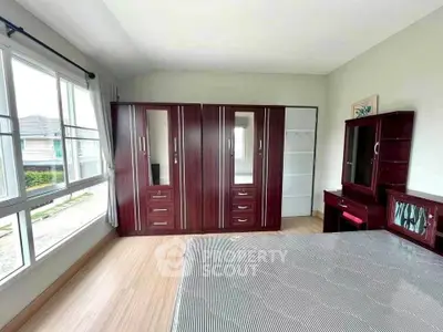 Spacious bedroom with large windows and elegant wooden furniture