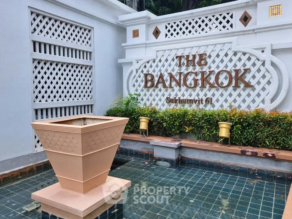 Elegant entrance of The Bangkok Sukhumvit 61 with decorative fountain and lush greenery.