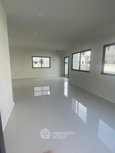 Spacious modern living room with large windows and glossy tiled floor