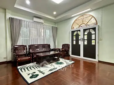 Elegant living room with wooden furniture and large window, perfect for family gatherings.
