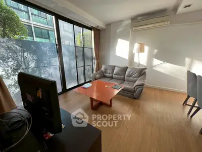 Spacious living room with natural light, modern furniture, and large windows in a stylish apartment.