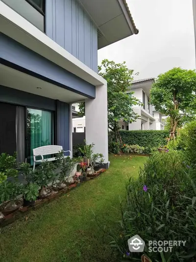 Charming garden view of modern townhouse with lush greenery and cozy outdoor seating.