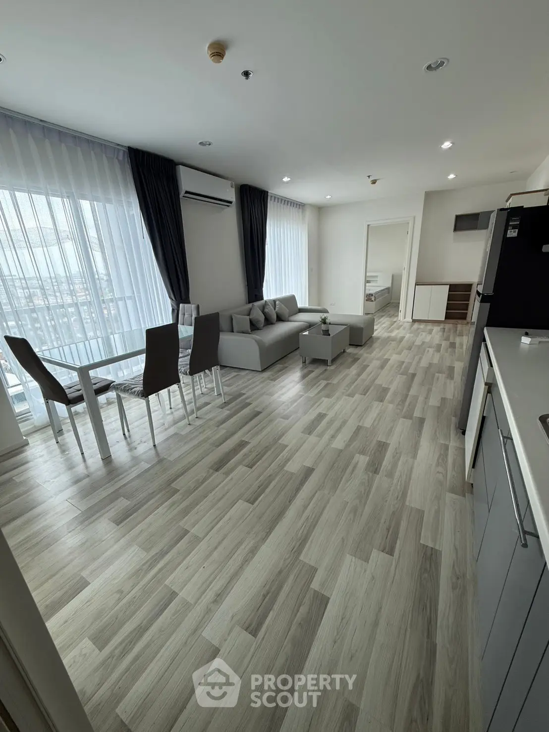 Spacious modern living room with open kitchen and elegant dining area, featuring large windows and stylish flooring.