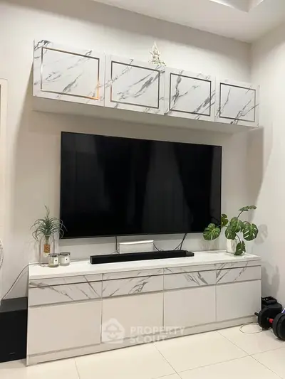 Modern living room with sleek marble cabinets and large flat-screen TV.