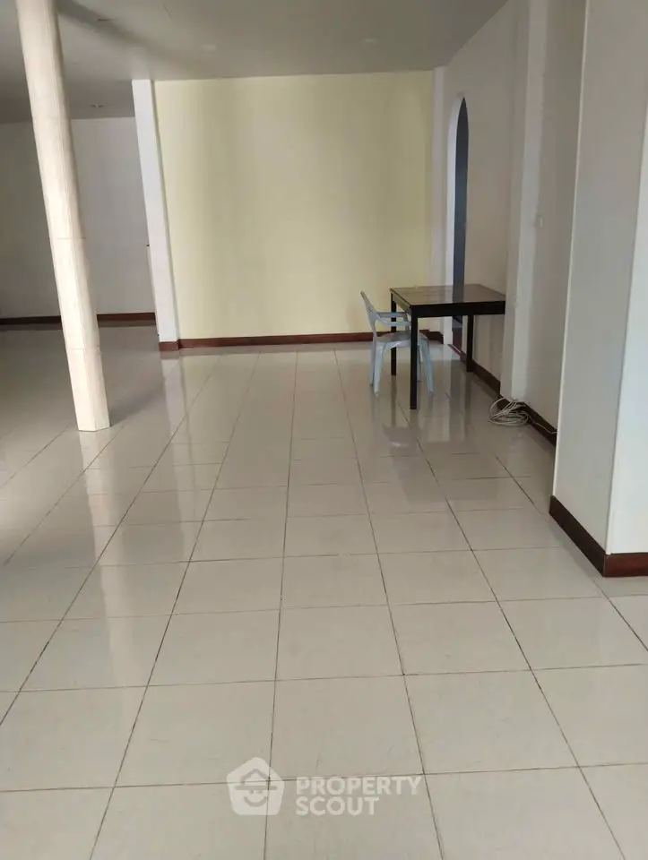 Spacious open-plan interior with tiled flooring and minimalist furniture.