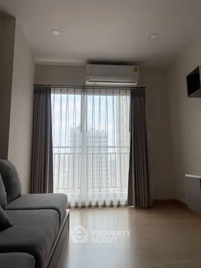 Modern living room with large window and city view, featuring sleek sofa and air conditioning unit.