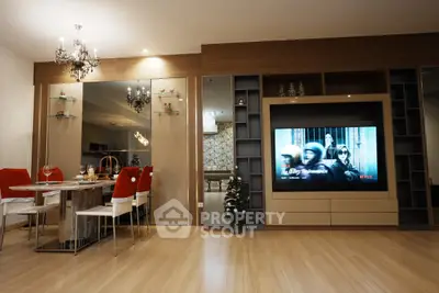 Modern living room with dining area and large TV, featuring elegant decor and wooden flooring.