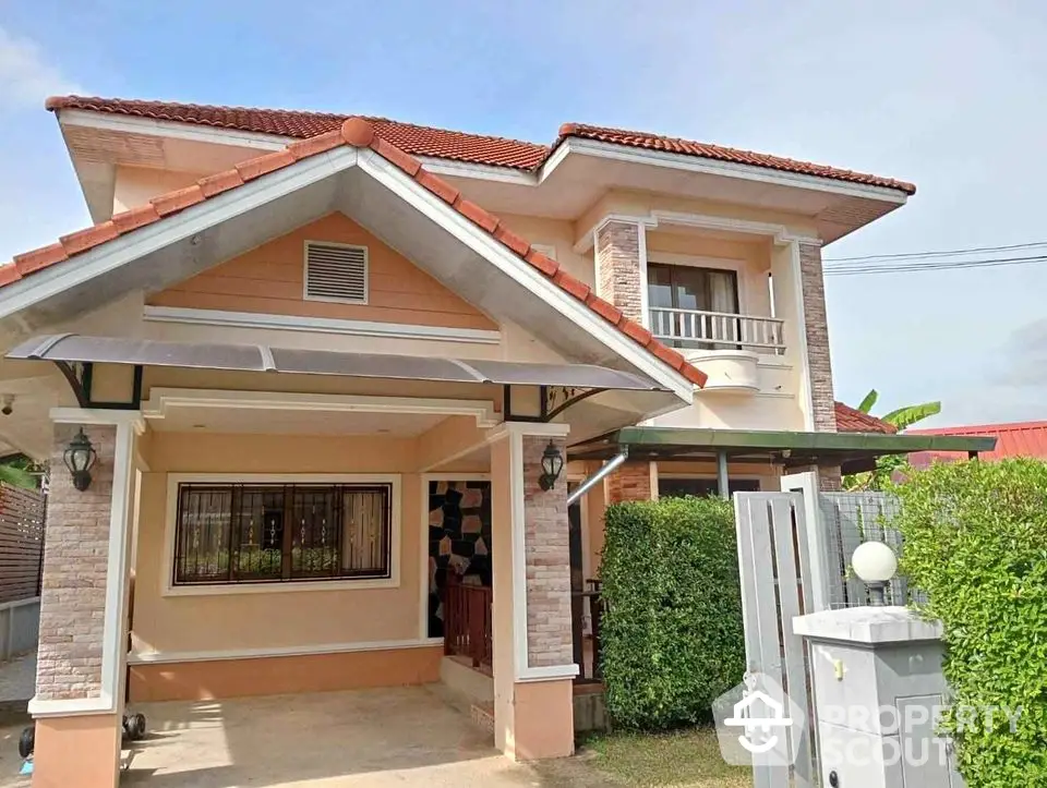 Charming two-story house with red roof and lush greenery, perfect for family living.