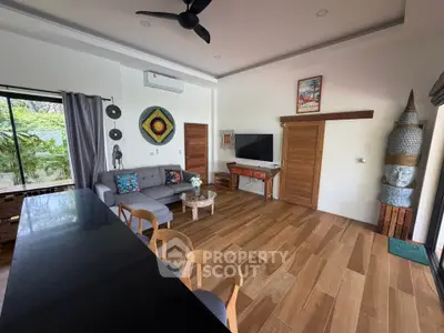 Stylish living room with modern decor and wooden flooring, featuring a cozy seating area and wall-mounted TV.