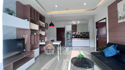 Modern living room with open kitchen, stylish decor, and natural light.