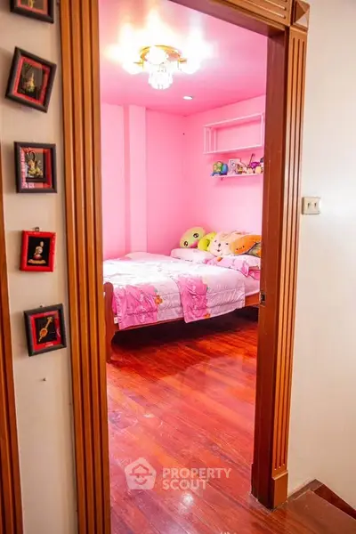 Charming pink-themed bedroom with wooden flooring and cozy decor.