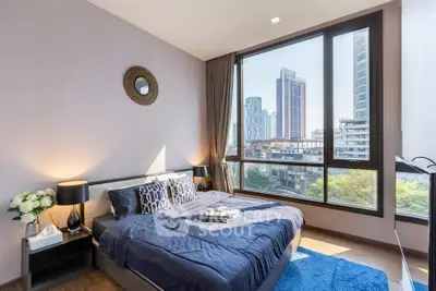 Modern bedroom with large windows offering stunning city views, stylish decor, and cozy ambiance.