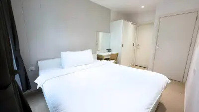 Modern minimalist bedroom with white bedding and sleek furniture design.