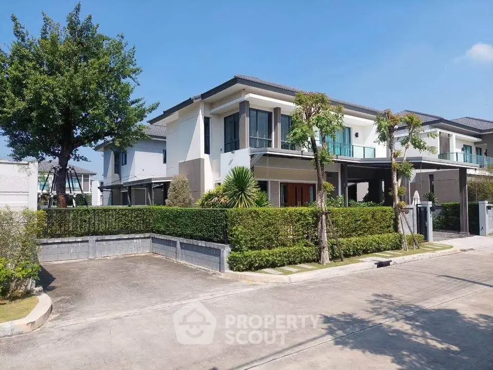 Modern two-story house with lush greenery and spacious driveway in a serene neighborhood.