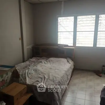 Cozy bedroom with natural light and tiled flooring, perfect for a comfortable living space.