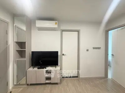 Modern living room with sleek TV setup and air conditioning in a stylish apartment.