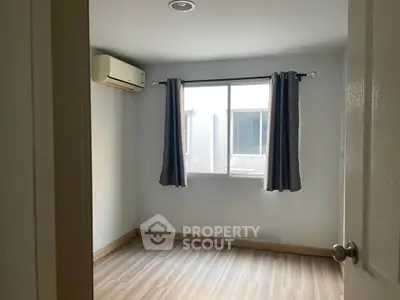 Bright empty bedroom with window and air conditioning unit.