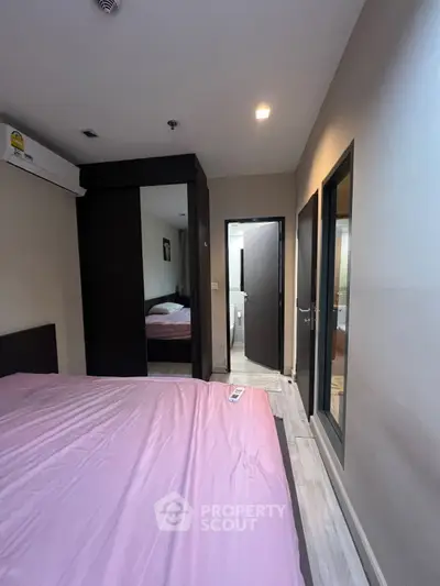 Cozy bedroom with pink bedding and modern wardrobe, featuring an ensuite bathroom.