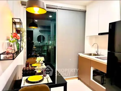 Modern kitchen with sleek design, featuring dining area and large fridge.