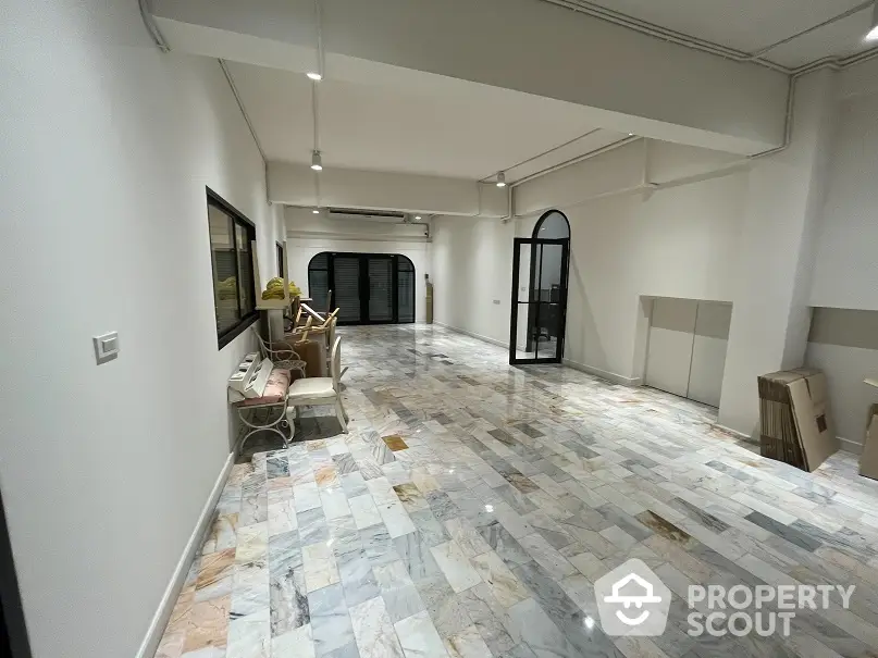 Expansive open-plan living space with polished multicolored marble flooring and high ceilings, perfect for custom interior design.