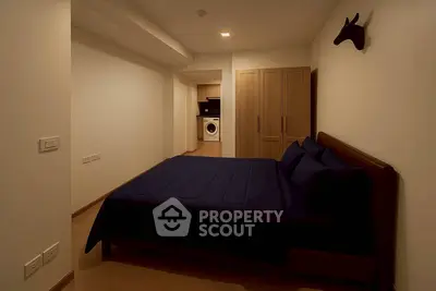 Cozy bedroom with modern decor and in-unit washing machine, perfect for urban living.