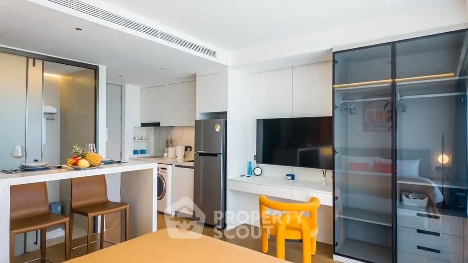 Modern studio apartment with sleek kitchen and cozy living area, featuring stylish furniture and appliances.