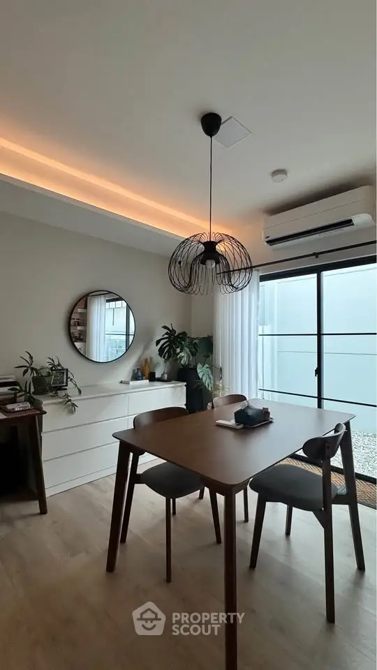 Modern dining area with stylish lighting and natural light from large window.