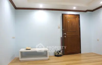 Minimalist interior with wooden door and light blue walls, featuring a small table and phone.
