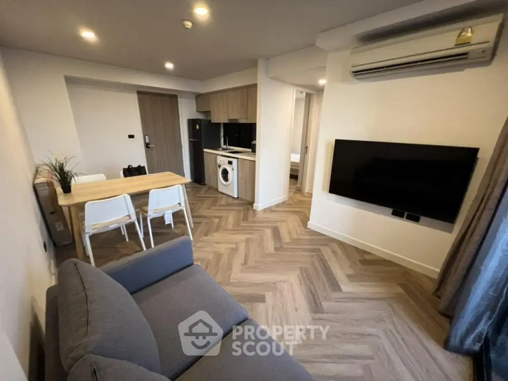 Modern living room with open kitchen, featuring sleek appliances and stylish decor.