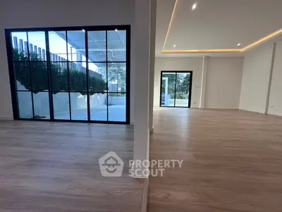 Spacious modern living area with large windows and wooden flooring