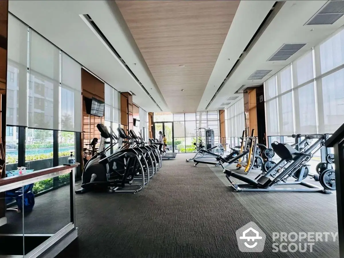 Spacious modern gym with state-of-the-art equipment and large windows for natural light.