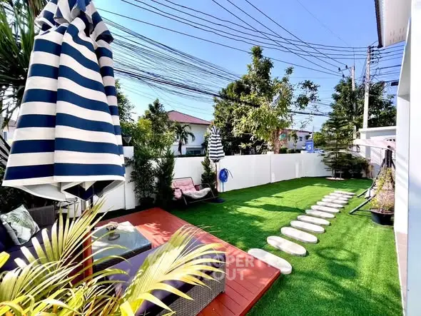 Charming backyard with lush green lawn, cozy seating, and vibrant umbrellas, perfect for outdoor relaxation.