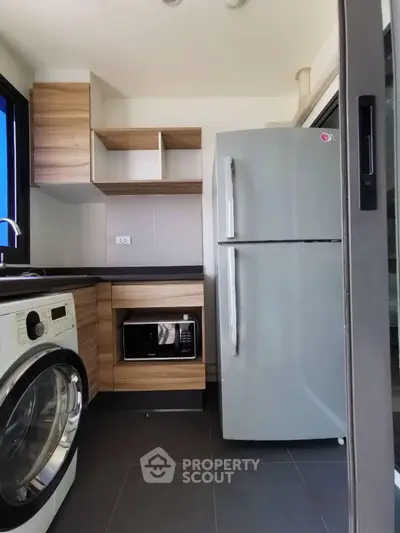 Modern compact kitchen with appliances including fridge, washing machine, and microwave.