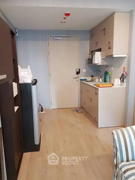 Compact modern kitchen with light wood flooring and sleek cabinetry in a cozy apartment.